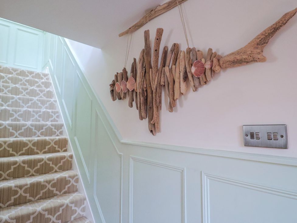 A staircase with a wooden wall decoration at Mayflower Cottage in Lyme Regis