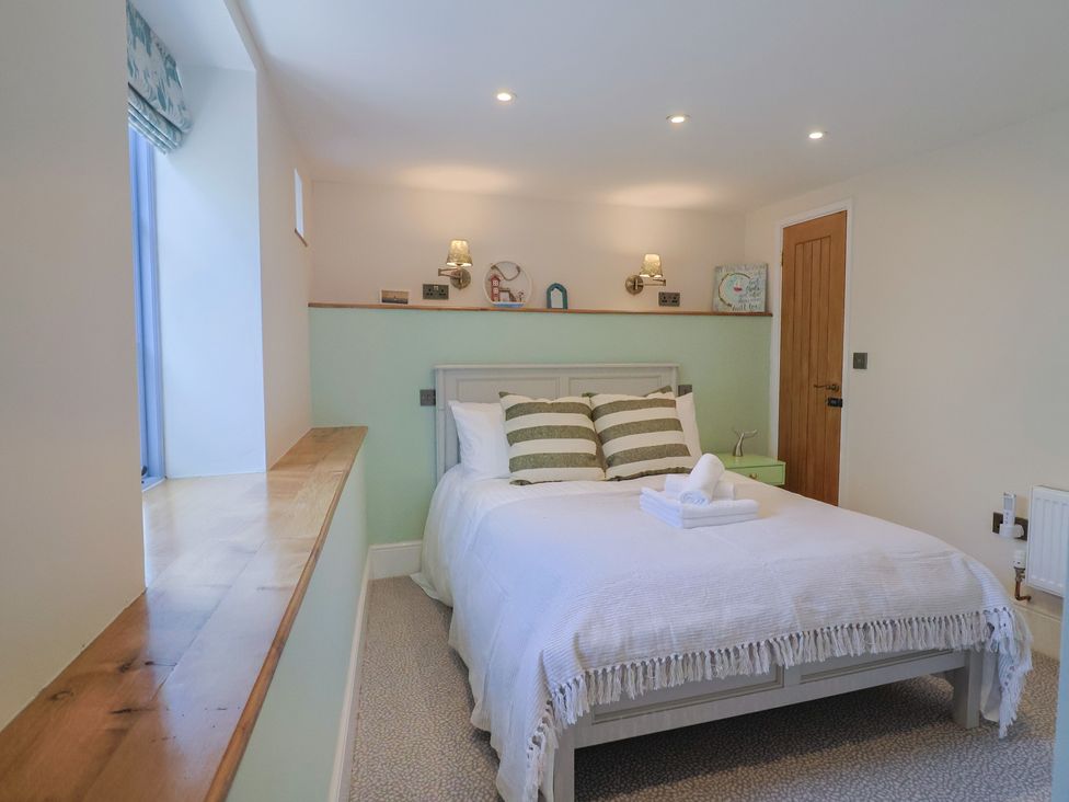 A bedroom with a double bed and pillows at Mayflower Cottage in Lyme Regis