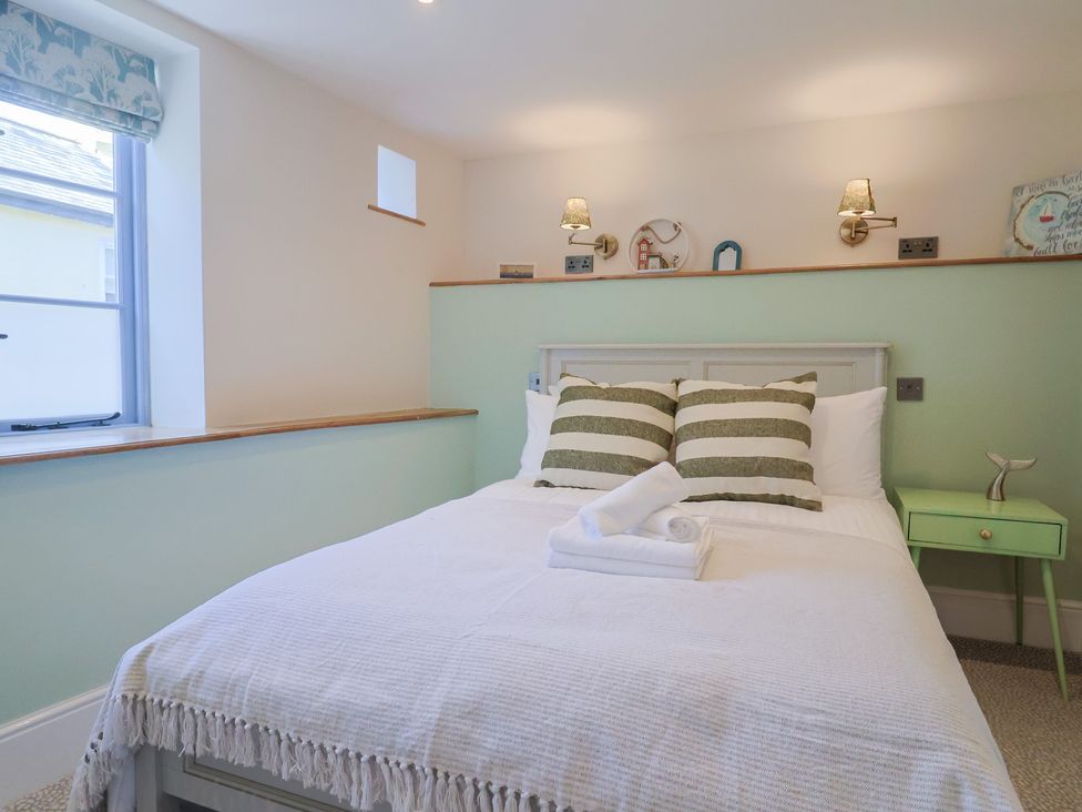 A bedroom with a bed, pillows, and a nightstand at Mayflower Cottage in Lyme Regis