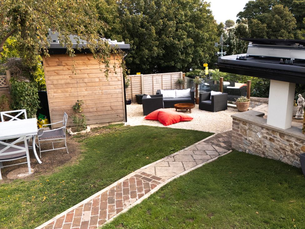 A garden with seating area and storage shed at Mayflower Cottage, Lyme Regis