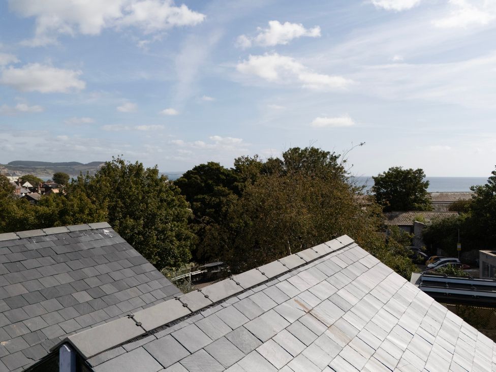 An outdoor view of roofs and trees with the sea in the background at Mayflower Cottage Lyme Regis
