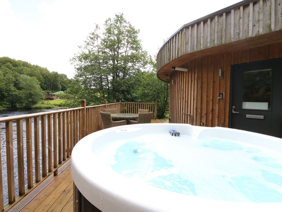 An outdoor area with a hot tub and seating at The Crannog in Killin