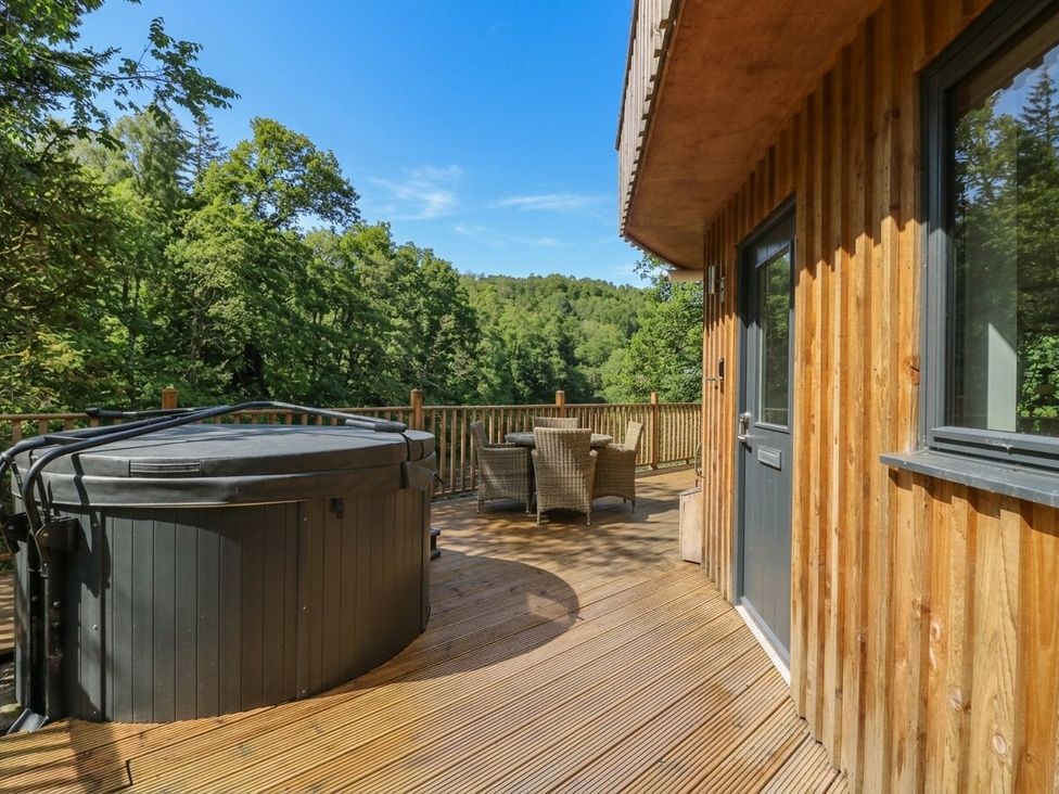 An outdoor area with a hot tub and seating at The Crannog in Killin