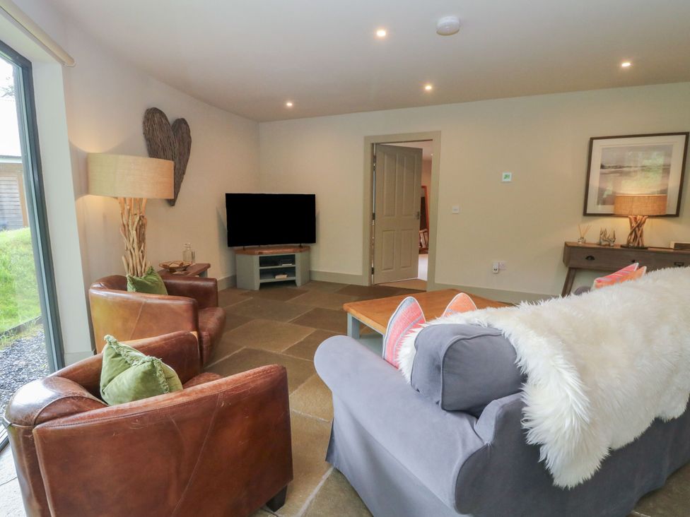 A living room with a sofa, armchairs, and a television at The Crannog in Killin