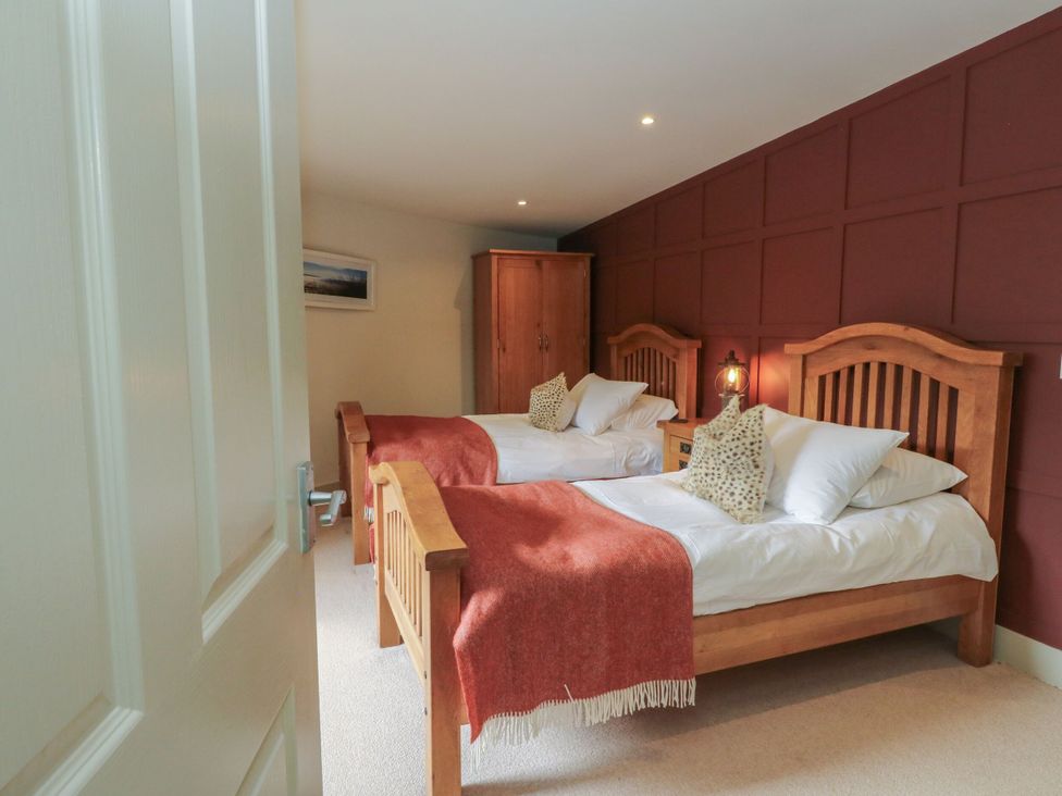 A bedroom with two beds and a wardrobe at The Crannog in Killin
