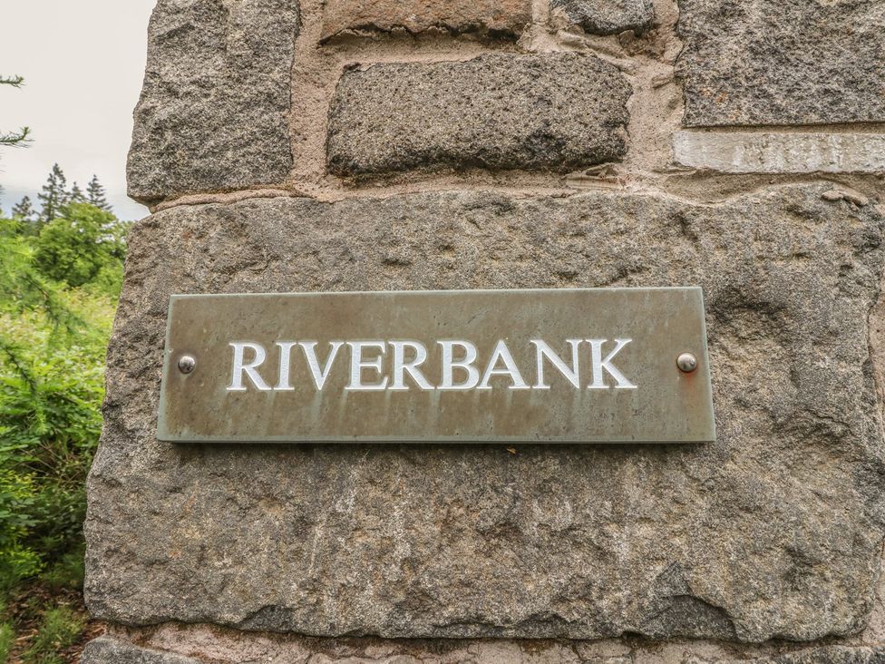A sign reading Riverbank on a stone wall at Riverbank Cottage in Killin