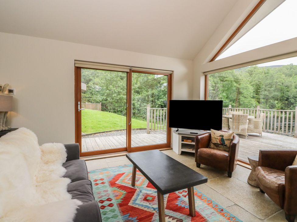 A living room with windows and a coffee table at Riverbank Cottage in Killin