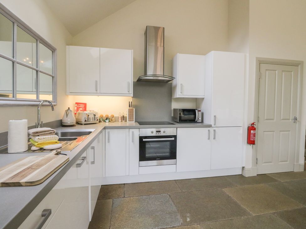 A kitchen with white cabinets and appliances at Riverbank Cottage in Killin