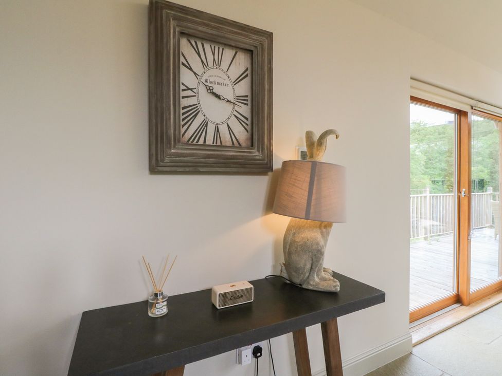 A living room with a clock and lamp at Riverbank Cottage in Killin