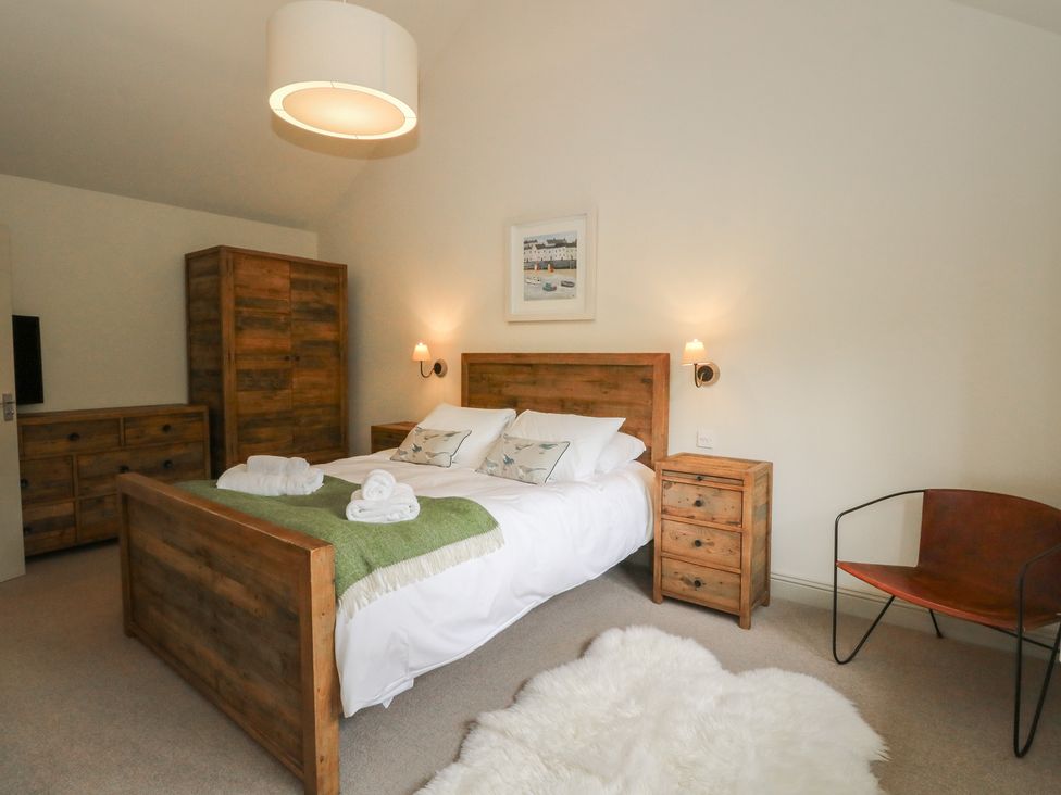 A bedroom with a wooden bed and furniture at Riverbank Cottage in Killin