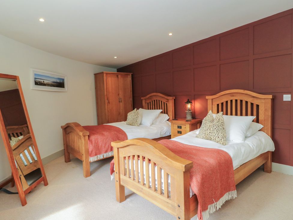 A bedroom with two beds and a wardrobe at Otter’s Holt in Killin