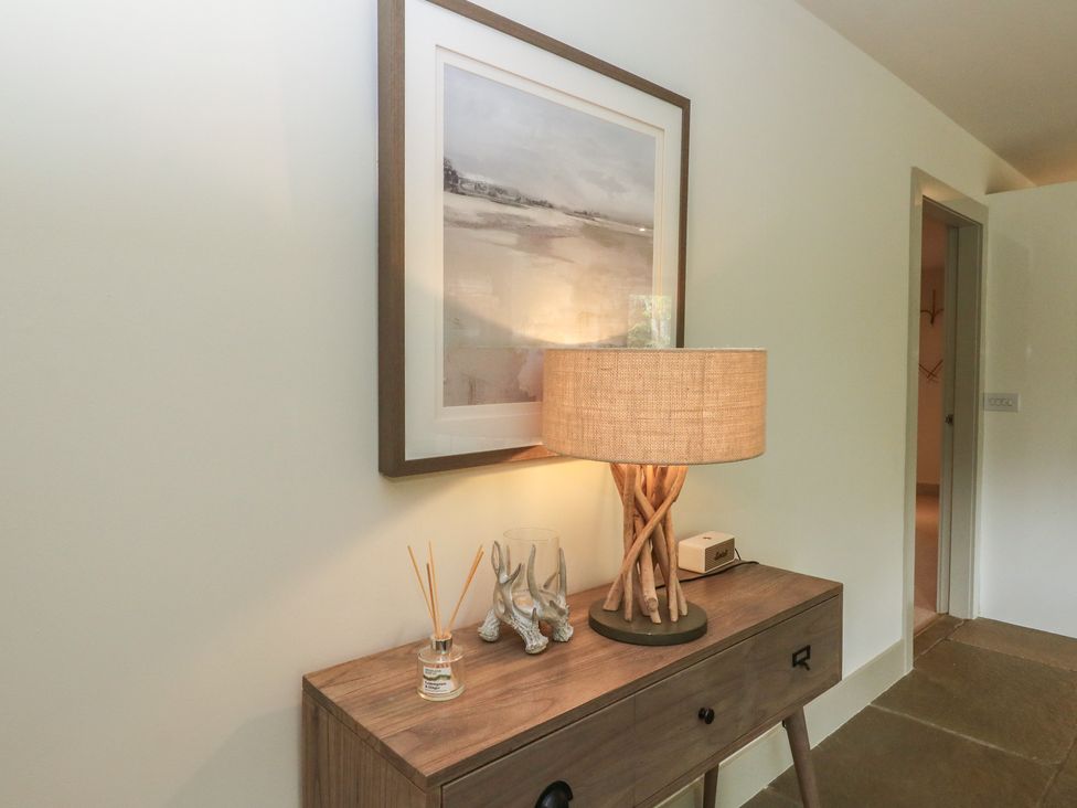 A hallway with a lamp and picture on a table at Otter’s Holt in Killin