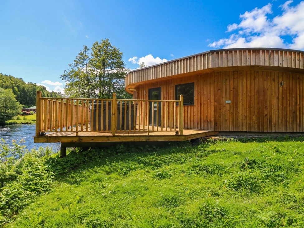 A wooden house with a deck facing a river at Otter’s Holt in Killin