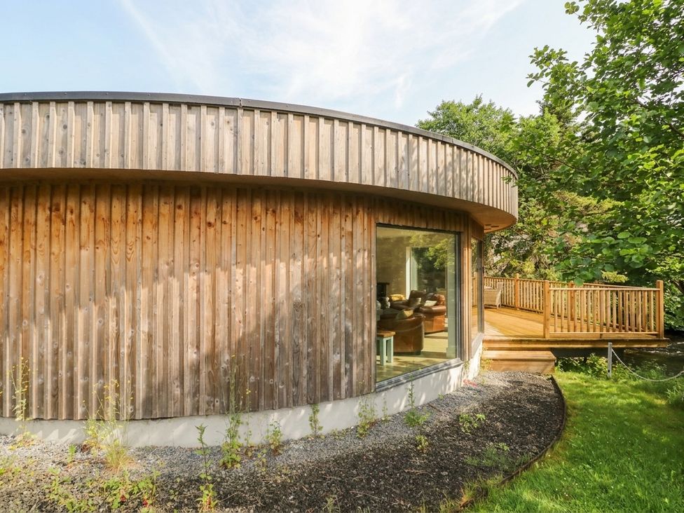 A wooden exterior of a house with a large window and decking area at Otter’s Holt in Killin
