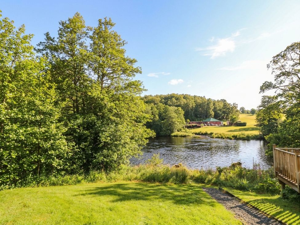 A view of trees and a river with a building at Otter’s Holt in Killin