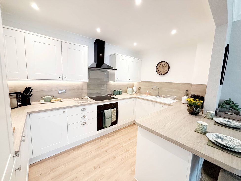 A kitchen with white cabinets and modern appliances at The Forbes in Torquay
