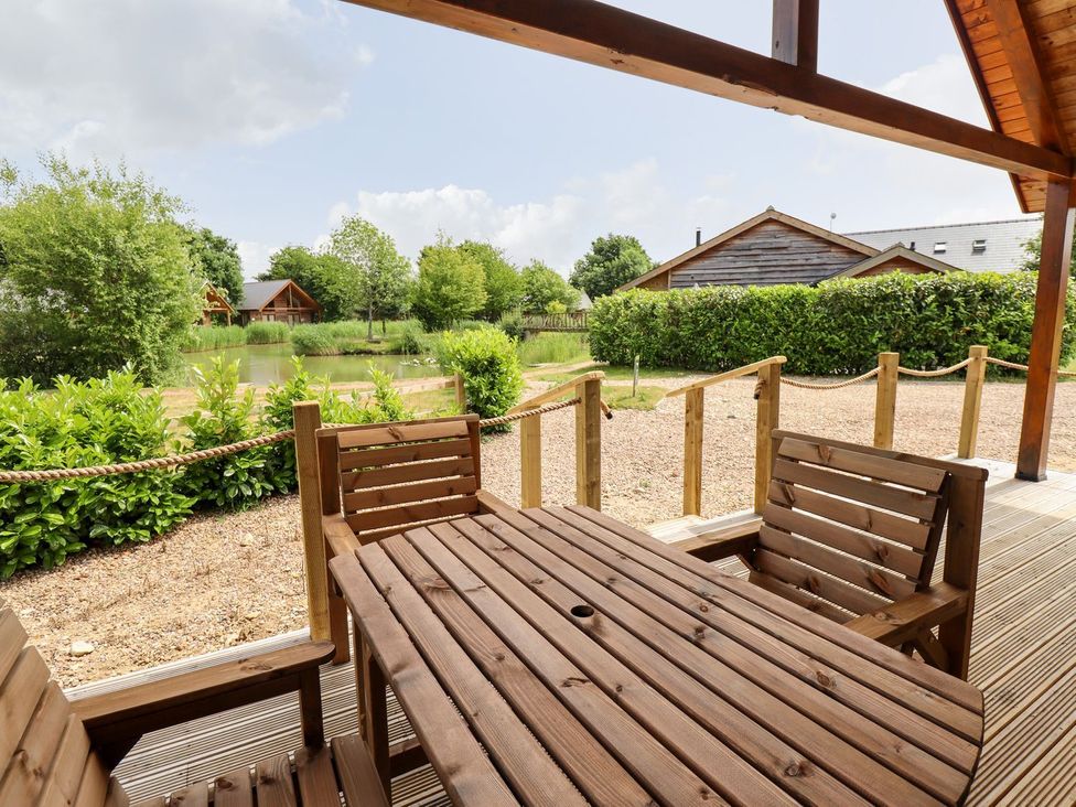 An outdoor seating area with wooden table and chairs near a pond at The Lilac Owl in Lincoln