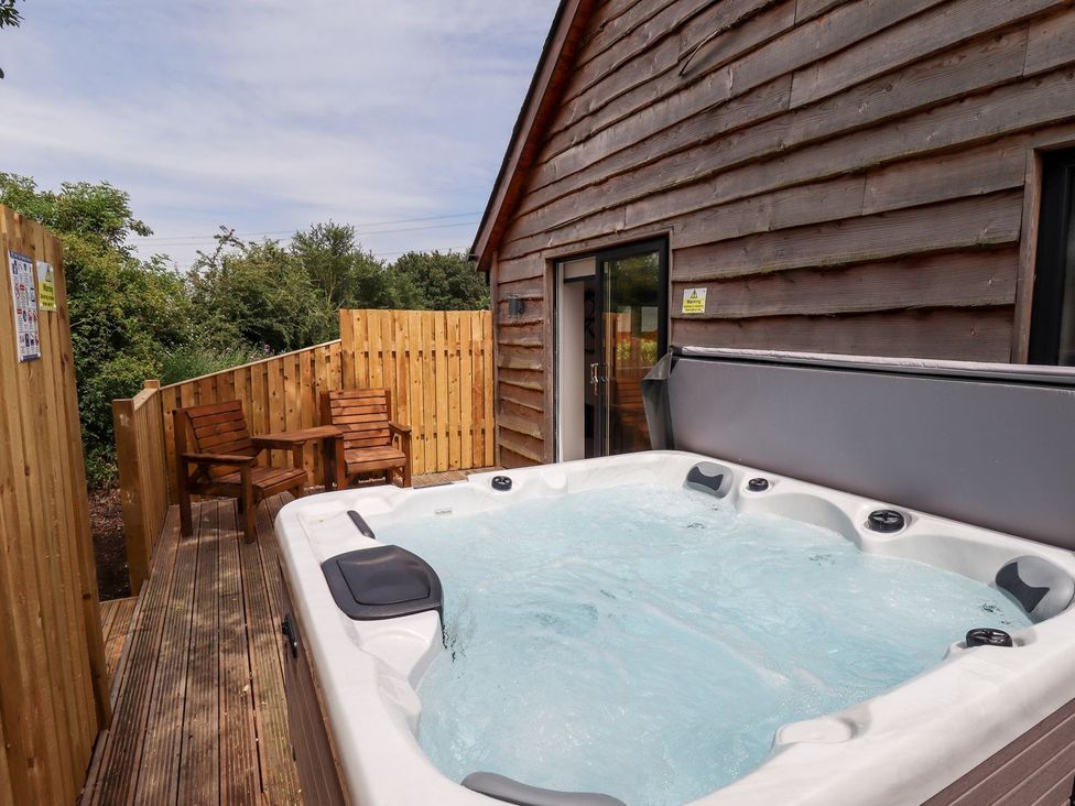 An outdoor area with a hot tub and wooden chairs at The Lilac Owl in Lincoln