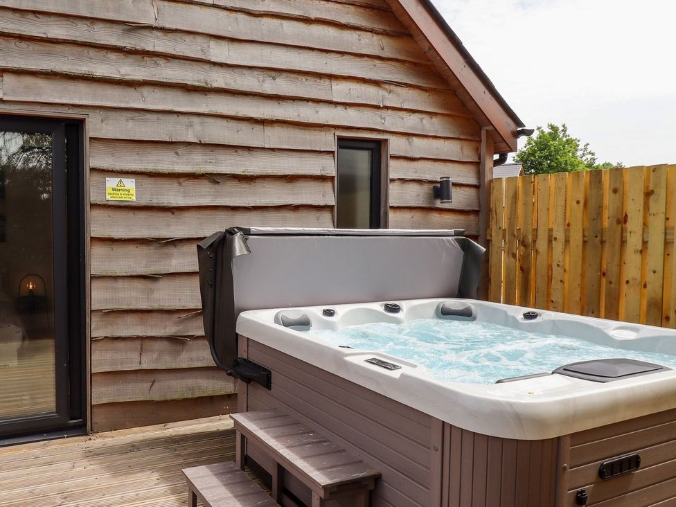 A hot tub on a deck next to a wooden fence at The Lilac Owl in Lincoln