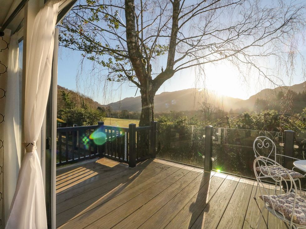 A deck with a view of mountains and a tree at Hollybirch in Crieff