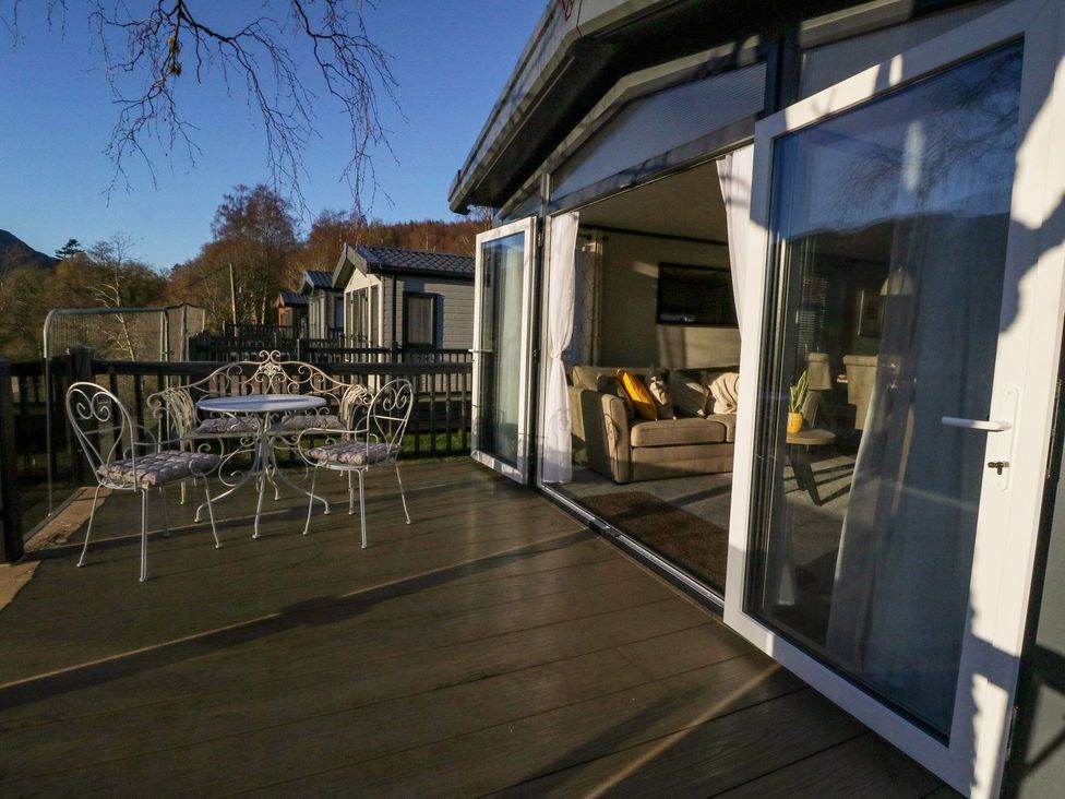 A deck with a table and chairs and a view into a living room at Hollybirch in Crieff