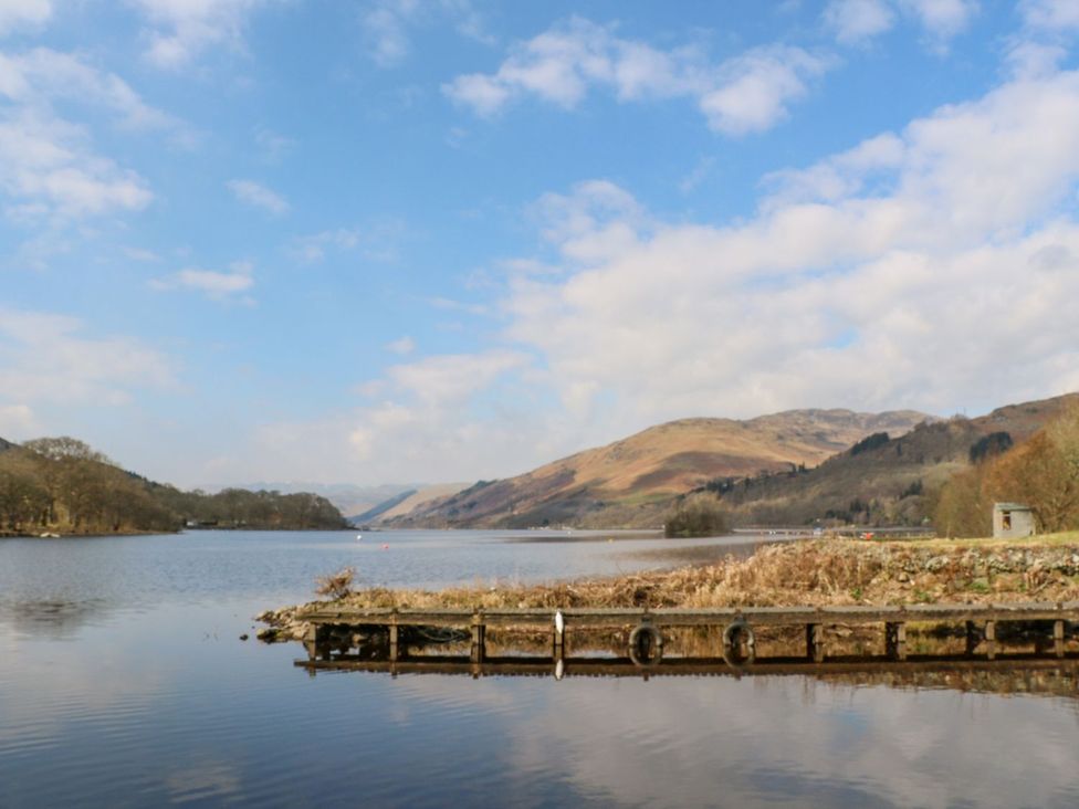 A lake with a pier and mountains in the background at Hollybirch in Crieff