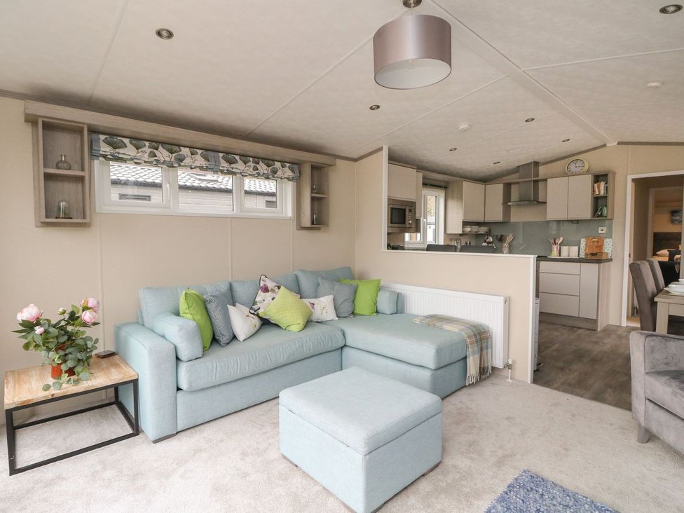 A living room with a sectional sofa and kitchen area at Rowan in Crieff