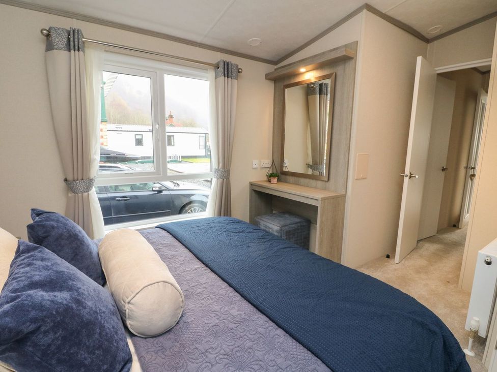A bedroom with a bed, window, mirror, and vanity unit at Rowan in Crieff