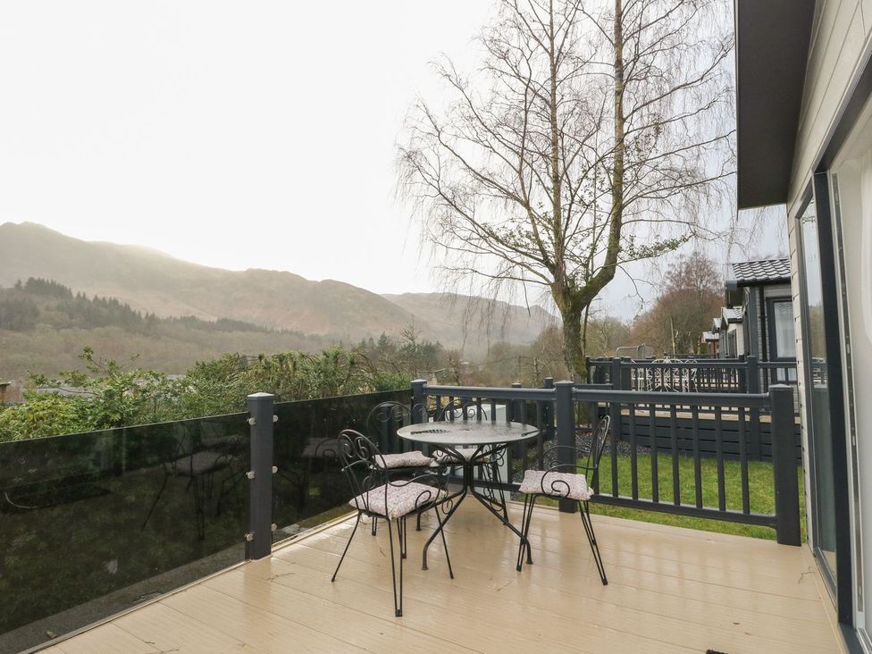 A deck area with a table and chairs overlooking mountains at Rowan in Crieff