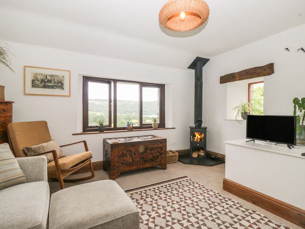 A living room with a fireplace and a television at Over Brow Cottage in Coniston