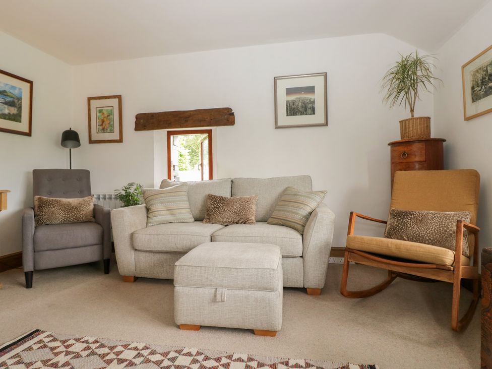 A living room with a sofa and armchair at Over Brow Cottage in Coniston