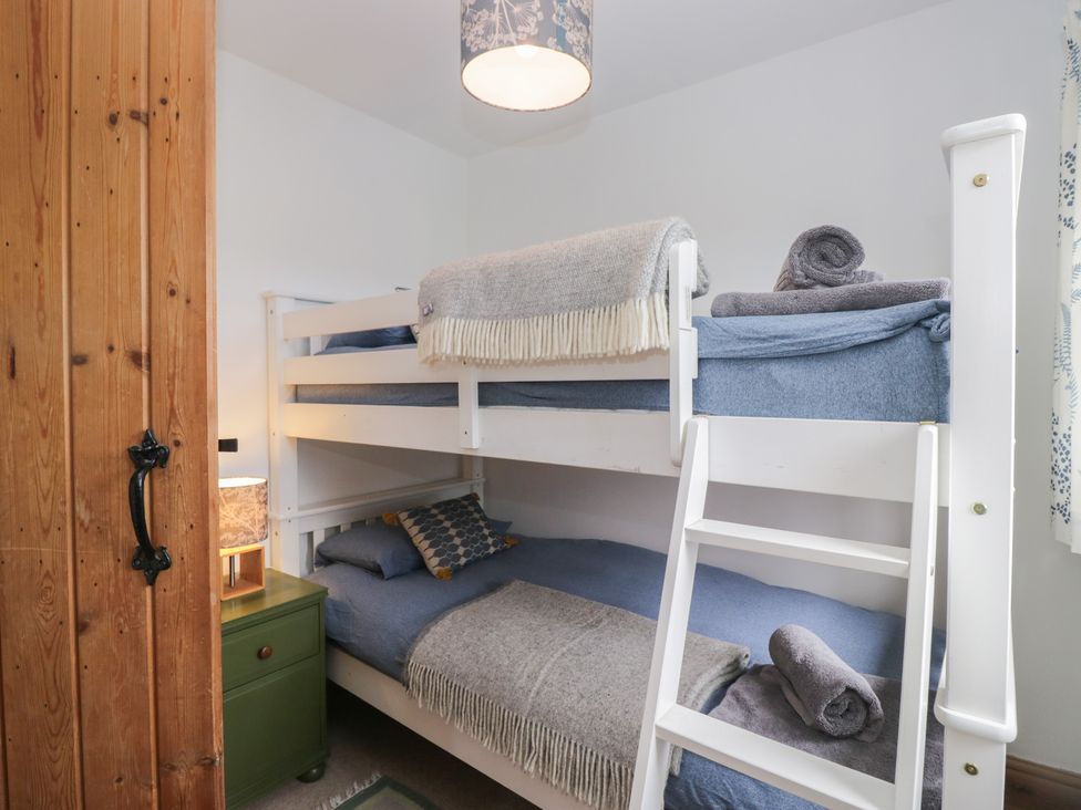 A bedroom with a bunk bed and nightstand at Over Brow Cottage in Coniston