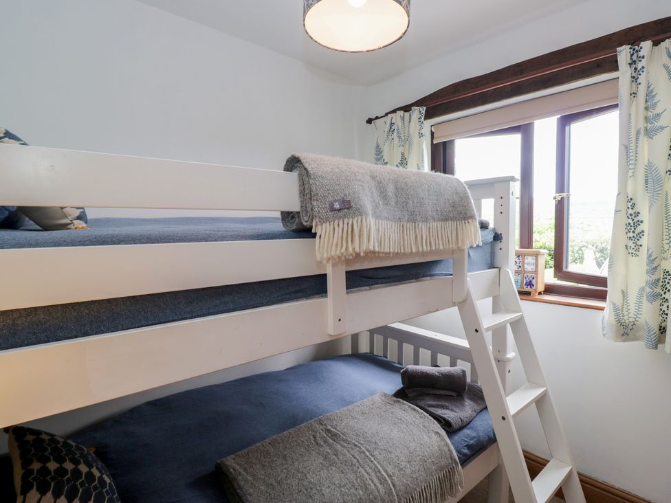 A bedroom with bunk beds and a window at Over Brow Cottage in Coniston