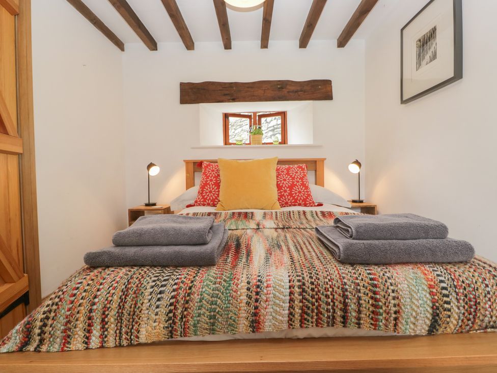 A bedroom with a bed and towels on top at Over Brow Cottage in Coniston