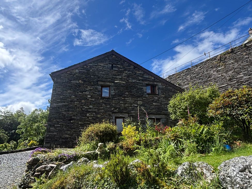 A stone house with windows and garden at Over Brow Cottage in Coniston