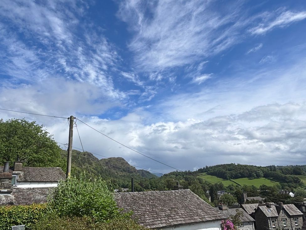 A view of rooftops and hills under a cloudy sky at Over Brow Cottage in Coniston