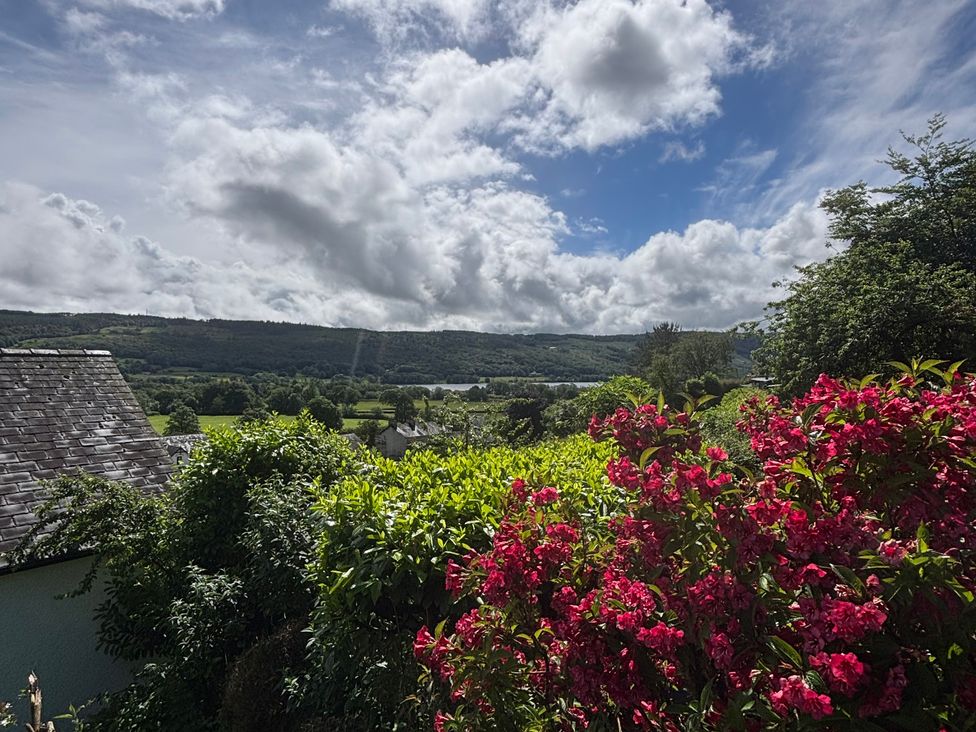 A view featuring flowers and trees with mountains in the background at Over Brow Cottage, Coniston