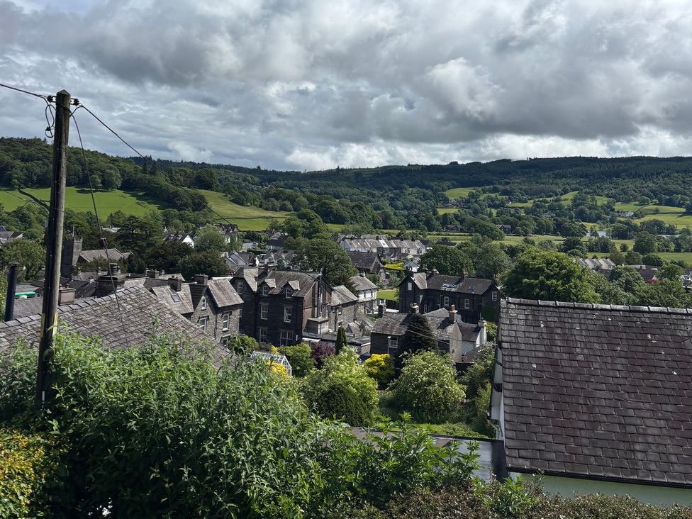 A view of houses and trees with mountains in the background at Over Brow Cottage in Coniston
