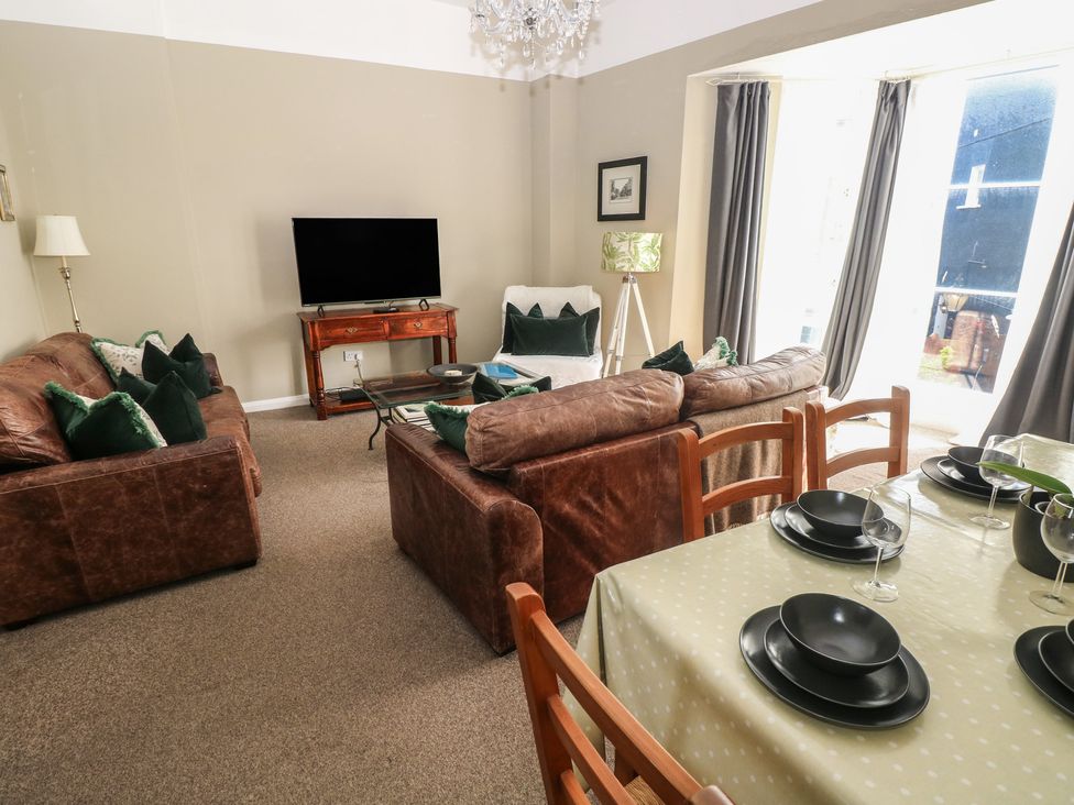 A living room with a television and dining area at Sea Suite