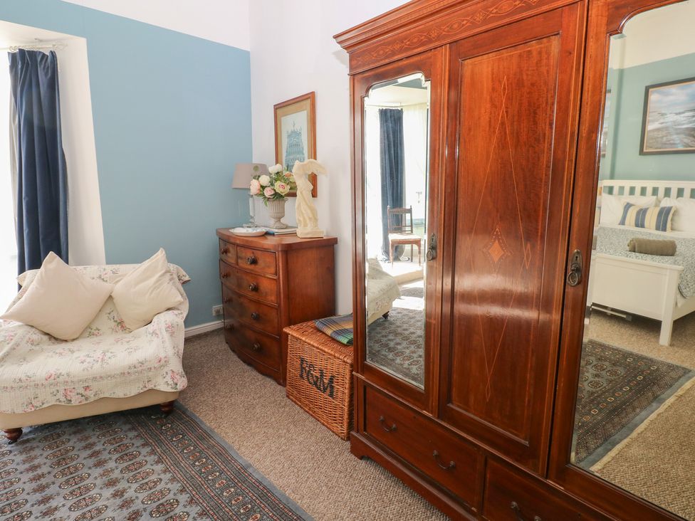 A bedroom featuring a wardrobe, chest of drawers, sofa and a decorative lamp at Sea Suite