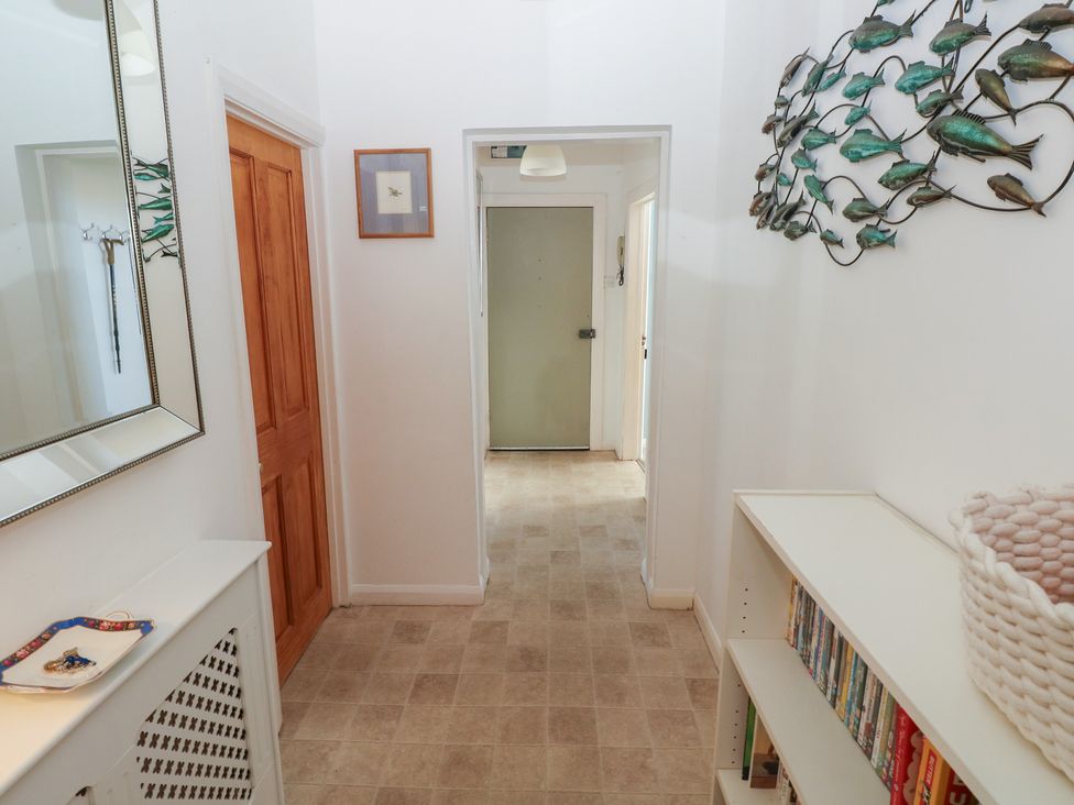 A hallway with a mirror and a bookshelf at Sea Suite