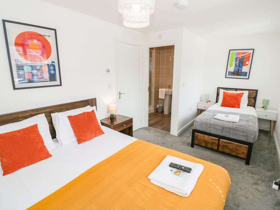 A bedroom with two beds and a bathroom door at 5 Warrington Lane Coventry