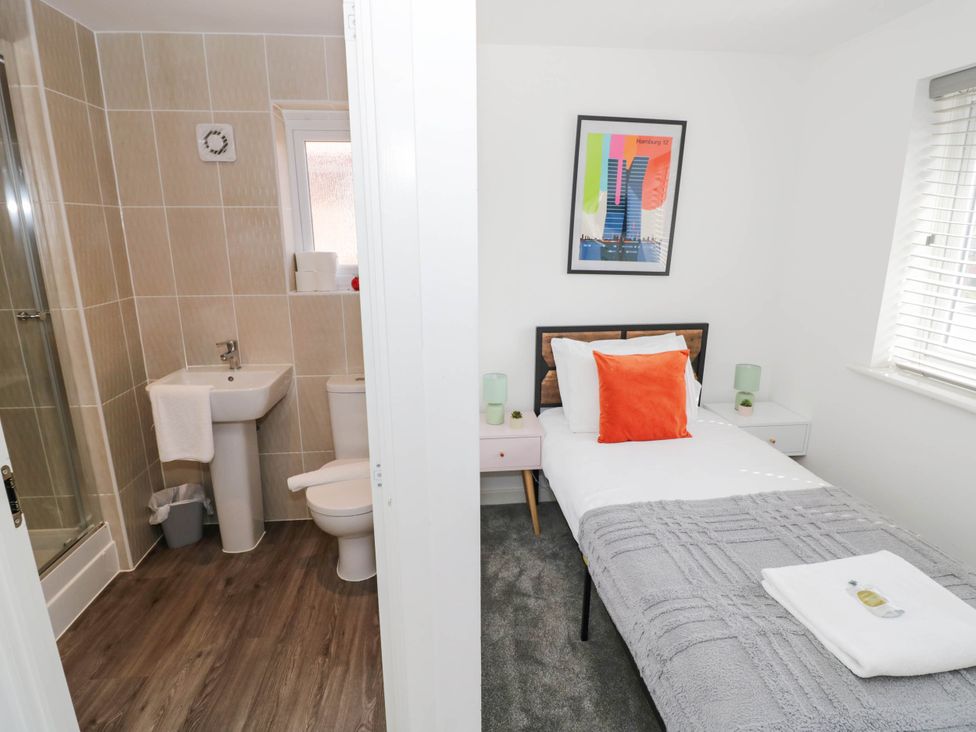 A bathroom with a shower and a bedroom with a single bed at 5 Warrington Lane Coventry