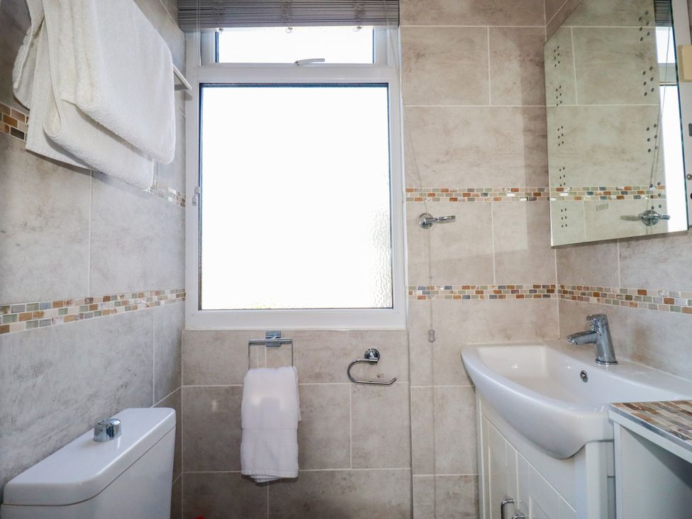 A bathroom with a sink, toilet, mirror, and towels at Two Bed Apartment No.4 Newquay