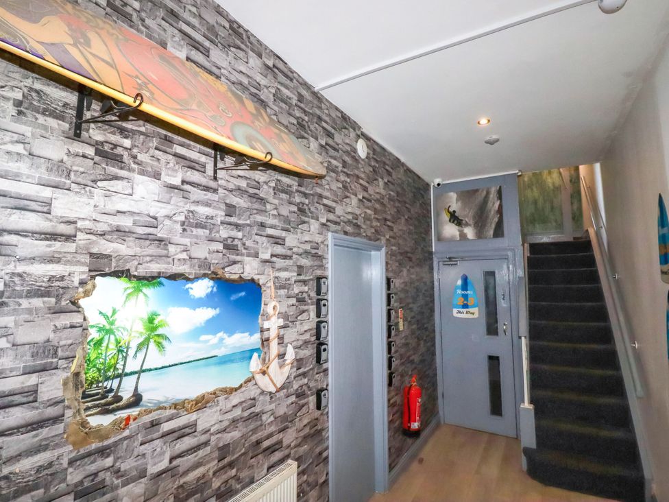 A hallway with a surfboard on the wall at Penthouse No.3 in Newquay