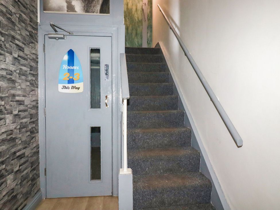 A staircase with a door labeled Rooms 2-3 at Penthouse No.3 in Newquay