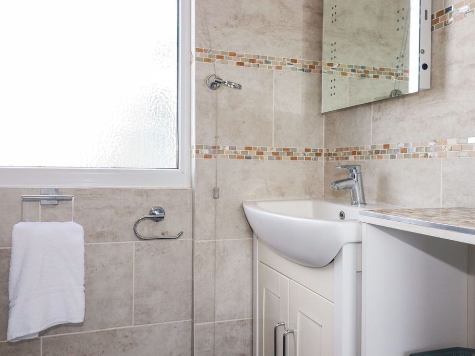 A bathroom with a sink, mirror, and towel rack at Penthouse No.3, Newquay