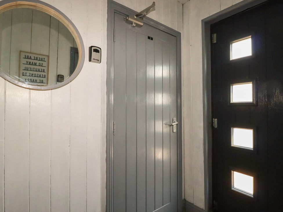 A hallway with a round mirror and two doors at Penthouse No.3 in Newquay