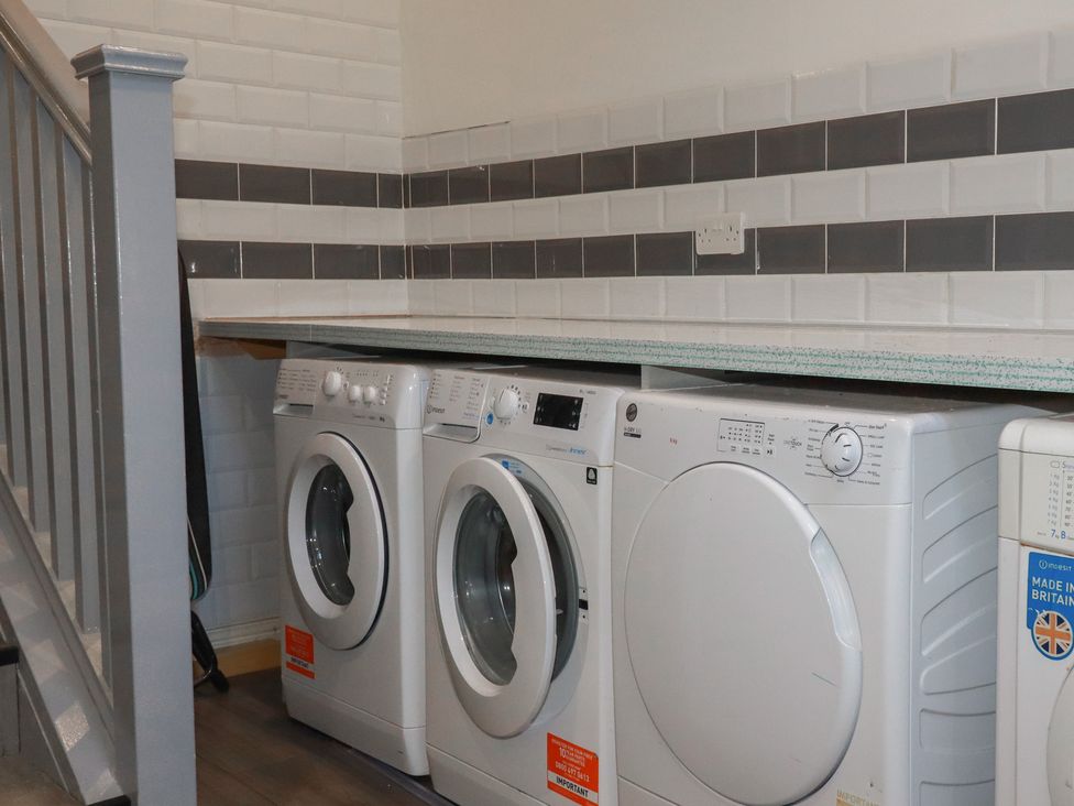 A laundry room with washing machines and a shelf at Penthouse No.3 in Newquay
