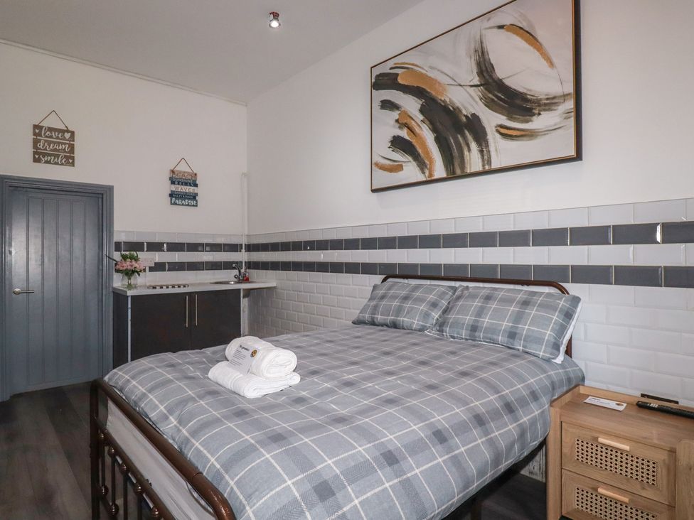 A bedroom with a bed and kitchenette at Penthouse No.3 in Newquay